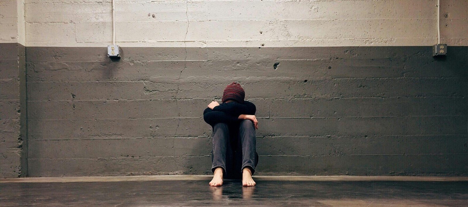 A person sitting alone in a corner, evoking themes of solitude and emotion.